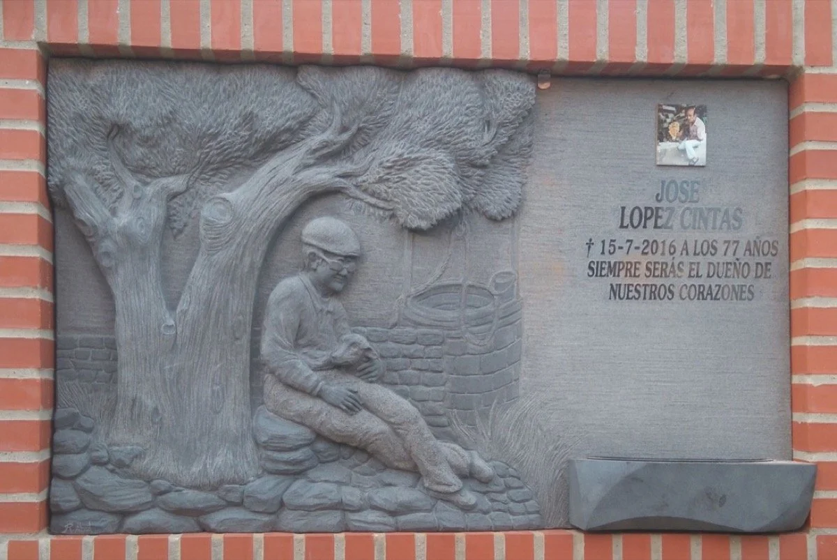 Lápida esculpida artesanalmente en granito negro con un acabado íntegramente mate, que contrasta elegantemente con la inscripción en relieve pulido. Un diseño único y profundamente personalizado, concebido codo a codo con la familia: la escena repres