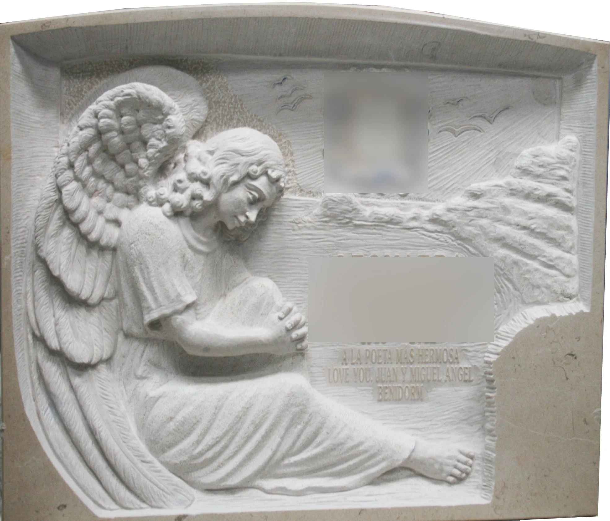 Lápida esculpida a mano en mármol Cenia, protagonizada por un detallado ángel con elaborados relieves en las alas y los mantos, acompañada de adornos en la parte posterior. Destaca por su cornisa de acabado redondeado tallada directamente de la misma