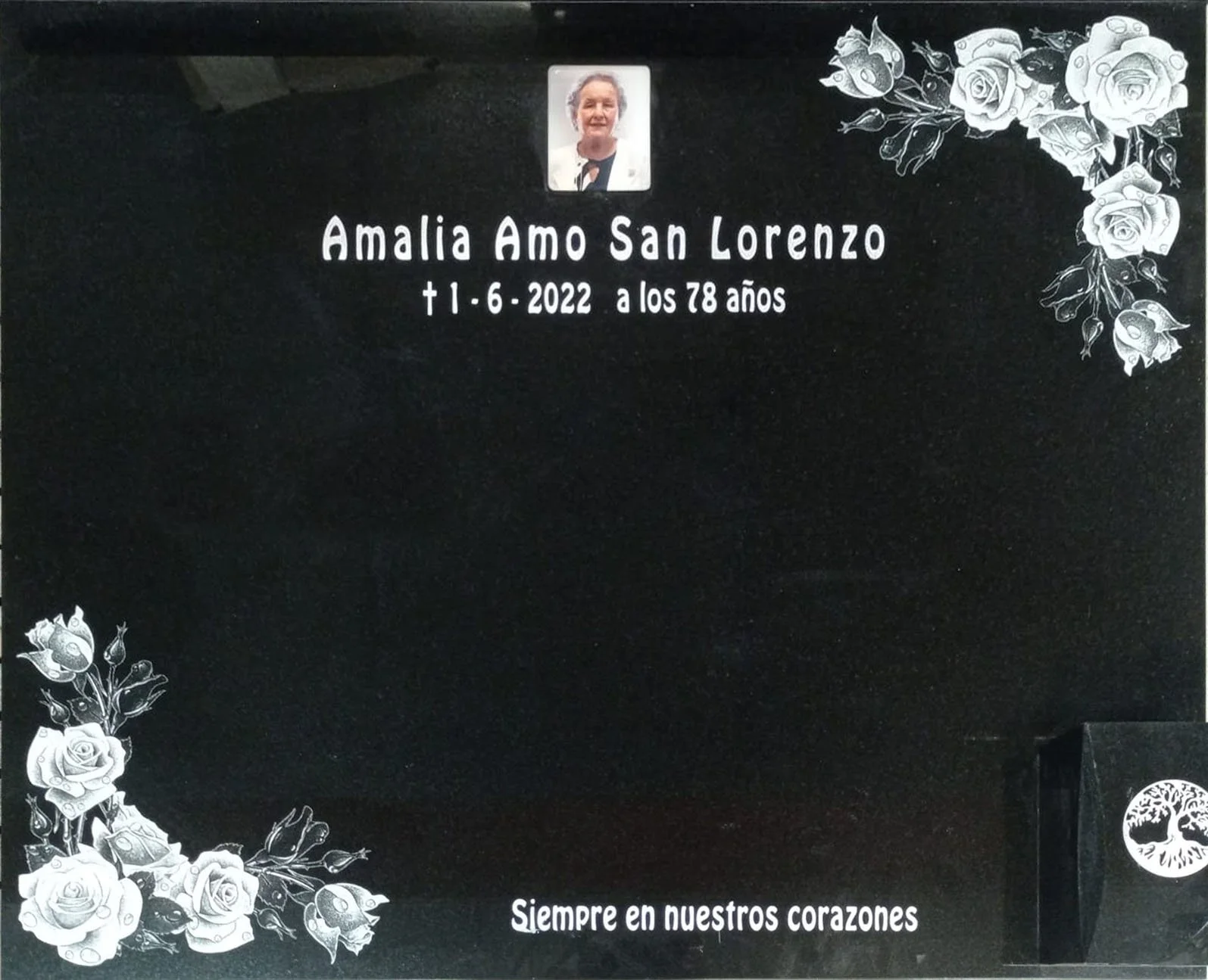 Lápida en granito negro pulido que incorpora un delicado grabado láser de alta definición, destacando unos finos adornos florales que enmarcan con elegancia dos esquinas. Un diseño sobrio, limpio y de gran precisión estética, realizado de manera arte