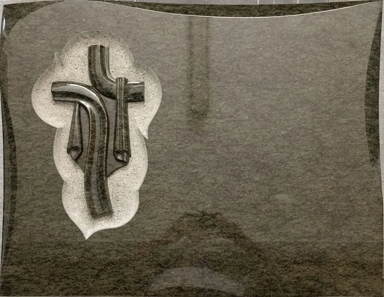 Lápida en granito con una cruz de manto tallada y pulida sobre un elegante fondo repicado artesanalmente. Una pieza de arte funerario que destaca por el contraste de texturas y el cuidado trabajo manual de escultura, elaborada en nuestro taller de Al