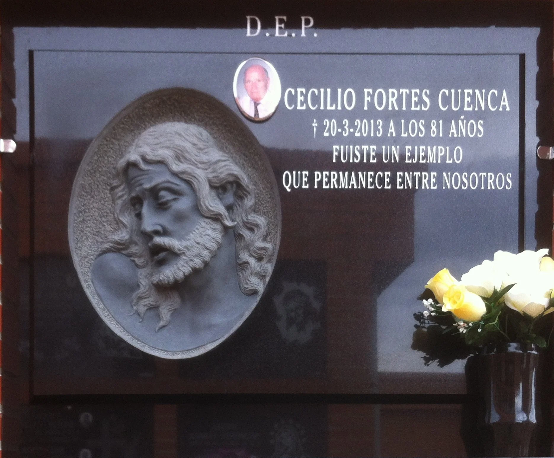Lápida de elegante granito negro presidida por una escultórico cabeza de Cristo tallada a mano. El diseño se completa con un espacio integrado para fotografía, inscripción personalizada y un búcaro a juego. Una obra de profunda devoción y delicada ma