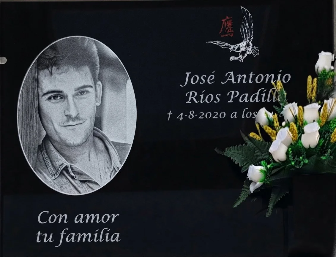 Lápida en granito negro profundo, personalizada mediante una técnica de grabado de altísima precisión que reproduce el retrato y busto del difunto con un realismo y detalle fotográfico excepcionales. La composición incorpora sutilmente dos elementos 