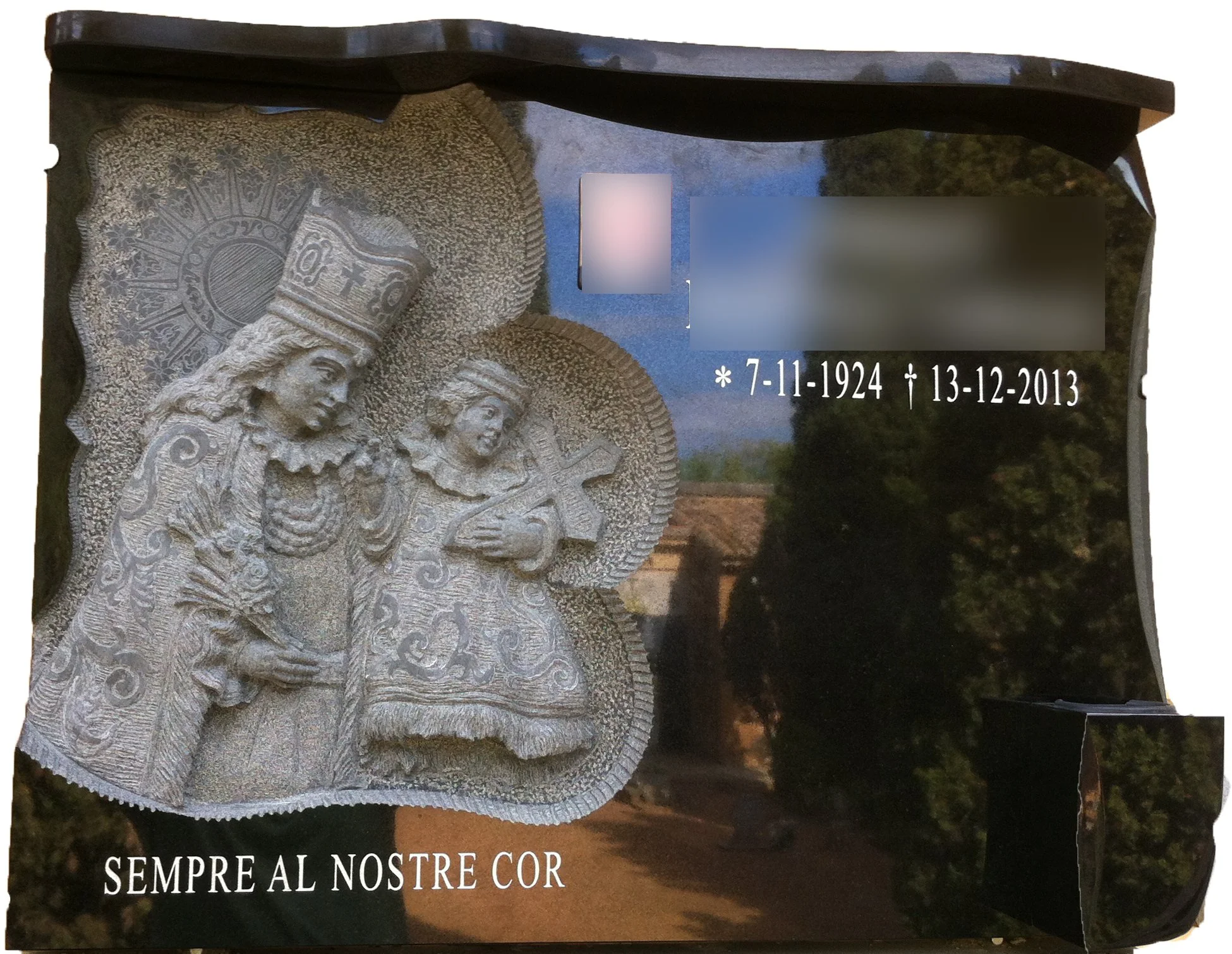 Lápida de granito negro con diseño abierto a la izquierda, relieve artesanal de la Virgen de los Desamparados de medio cuerpo, cornisa, búcaro y biseles. Obra tallada a mano por el escultor Raúl Abad en nuestro taller de Alfara del Patriarca (Valenci