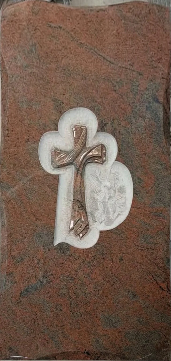 Lápida doble en granito rojo multicolor con cruz tallada y pulida sobre un elegante fondo repicado artesanalmente. El diseño se completa con el detalle de una escultura en el lateral, aportando un toque de distinción y solemnidad. Obra de arte funera