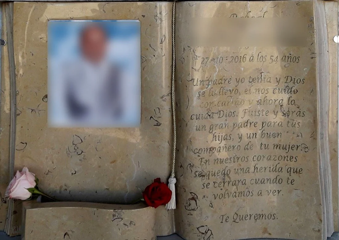 Lápida en mármol de Ulldecona tallada en forma de Biblia con separador de hojas, páginas marcadas en los laterales, gran foto cerámica incrustada y jardinera sobrepuesta, con acabado completamente pulido. Obra tallada a mano por el escultor Raúl Abad