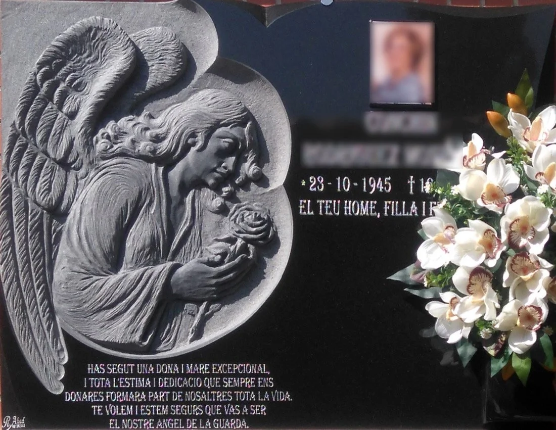 Lápida de granito negro con escultura en relieve de un ángel con una rosa en las manos, diseño de contorno abierto y búcaro sobrepuesto. Obra tallada a mano por el escultor Raúl Abad en nuestro taller de Alfara del Patriarca (Valencia).