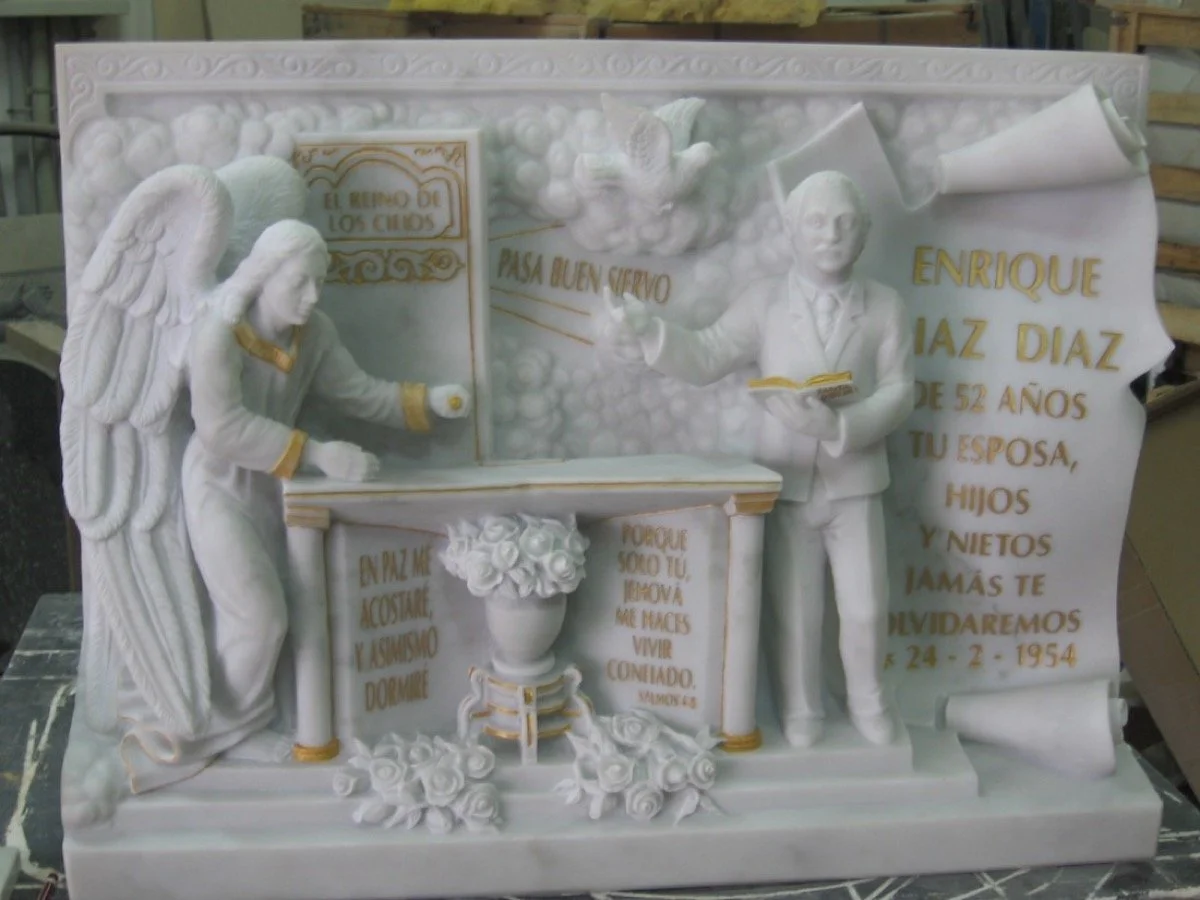 Lápida esculpida artesanalmente en noble mármol blanco Carrara, que recrea con impresionante nivel de detalle la escena de un pastor evangélico gitano predicando ante una mesa de altar, sosteniendo la biblia . La obra se completa con una inscripción 