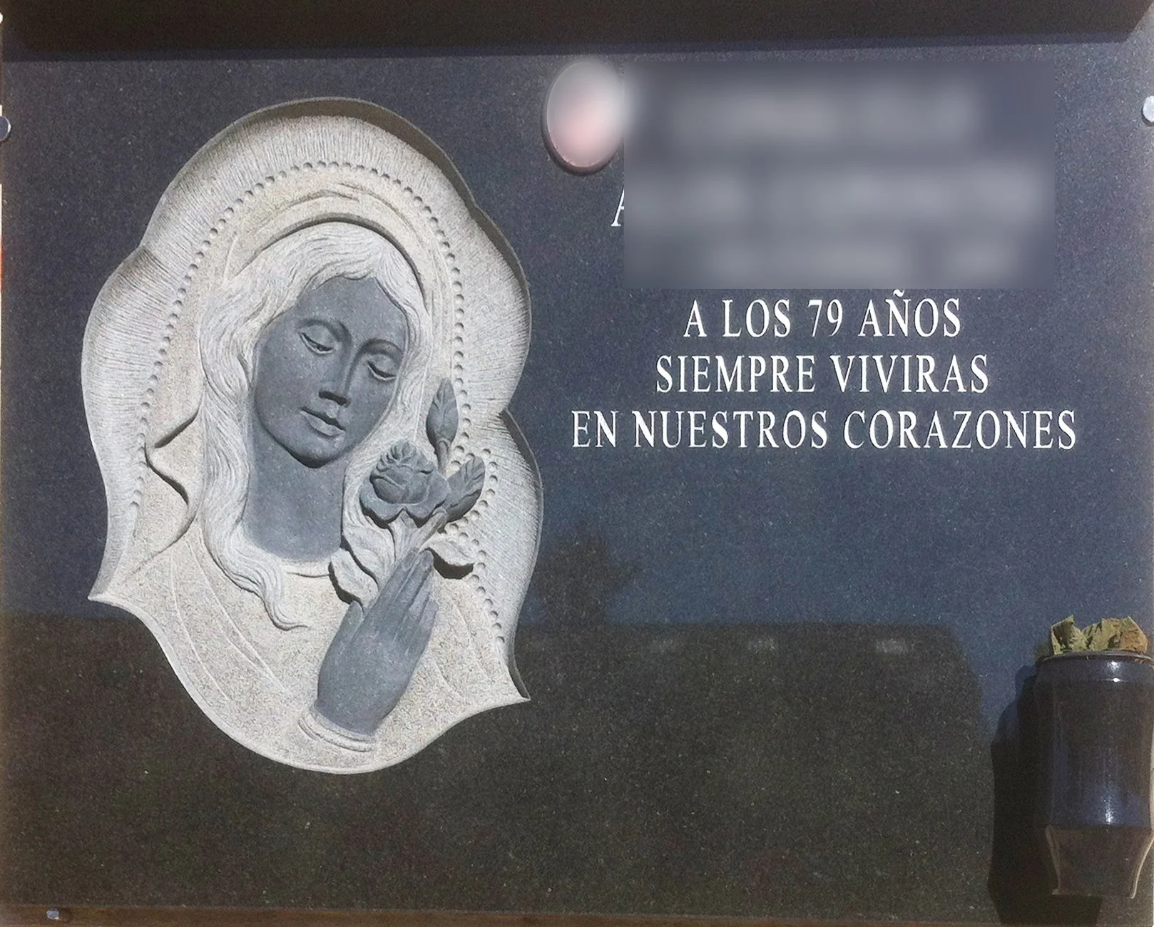 Lápida de distinguido granito negro, protagonizados por una escultura tallada íntegramente a mano de la Virgen sosteniendo una rosa entre sus manos. La obra se completa con un espacio reservado para la fotografía e inscripción personalizada. Una piez
