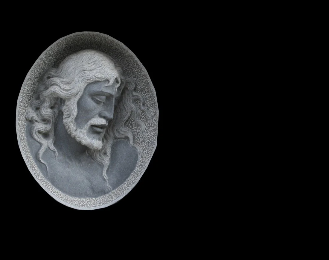 Lápida con escultura en relieve de cabeza de Cristo tallada a mano en granito. Obra artesanal realizada por el escultor Raúl Abad en nuestro taller de Alfara del Patriarca (Valencia).