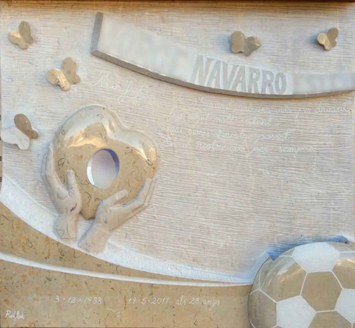 Lápida esculpida artesanalmente en noble mármol de Ulldecona, fruto de un diseño muy especial creado de la mano de la familia. La obra está protagonizada por unas manos que sostienen un corazón, en cuyo interior se integra la fotografía del difunto, 