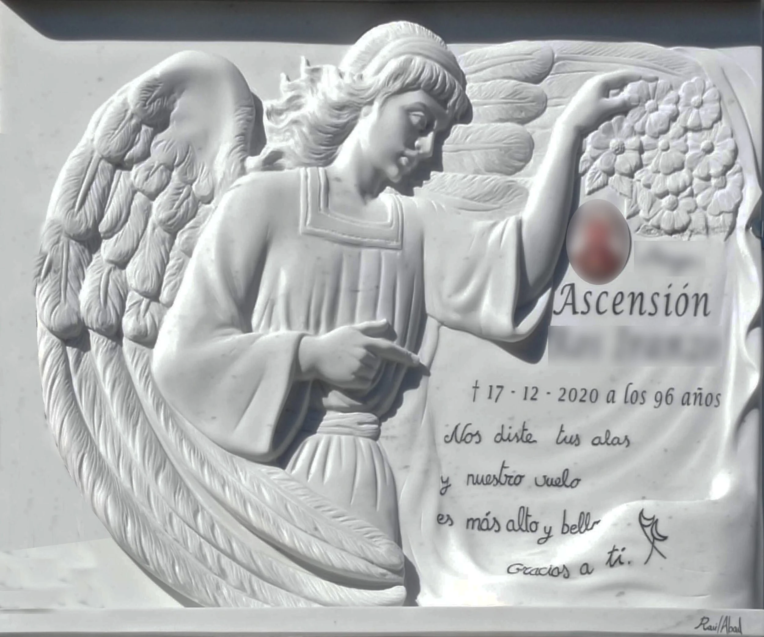 Lápida tallada en mármol blanco con detalle de ángel y flores, acompañada de una jardinera tallada directamente de la misma piedra, inscripción hecha a mano y acabados con cornisa y repisa. Una pieza totalmente personalizada para la familia, elaborad