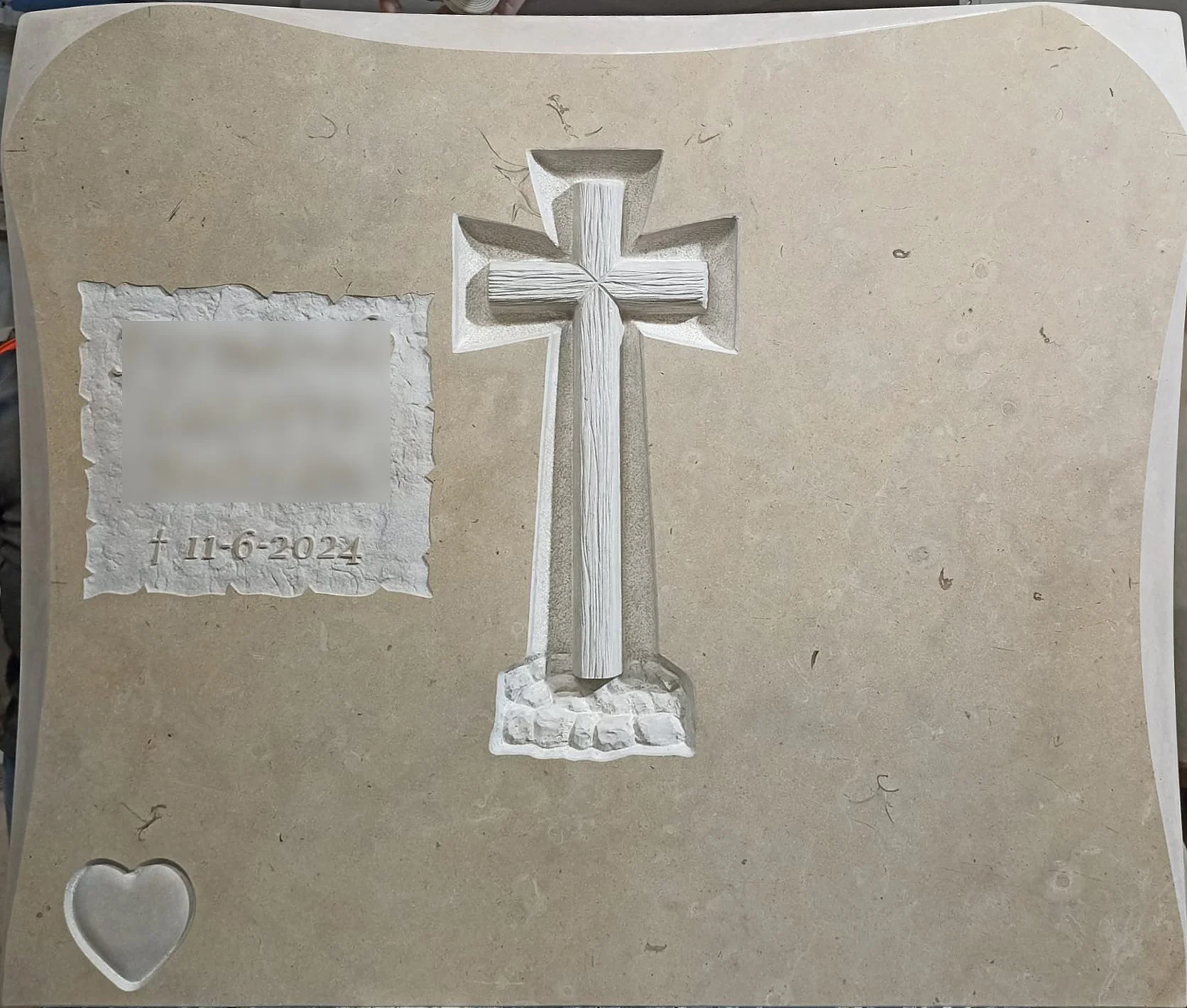 Lápida en mármol de Ulldecona con una cruz tallada en el centro con acabado mate y un detallado relieve de piedras en su base. El diseño se completa con un corazón en bajorrelieve en mate, elegantes biseles también en mate y un acabado con inscripcio