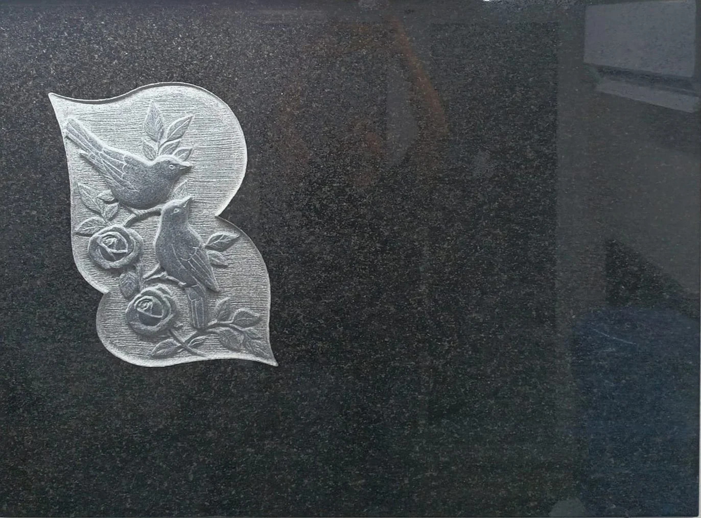 Escultura en relieve de ramo de flores tallada a mano en granito negro. Obra artesanal realizada por el escultor Raúl Abad en nuestro taller de Alfara del Patriarca (Valencia).