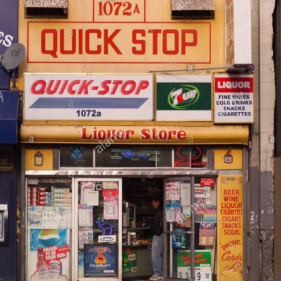 A liquor store front with multiple signs, including a large yellow sign saying 'QUICK STOP' and smaller signs advertising beer, wine, liquor, cigarettes, snacks, sodas, and 7UP branding. The store has a glass entrance with a person inside and various product advertisements on the door.