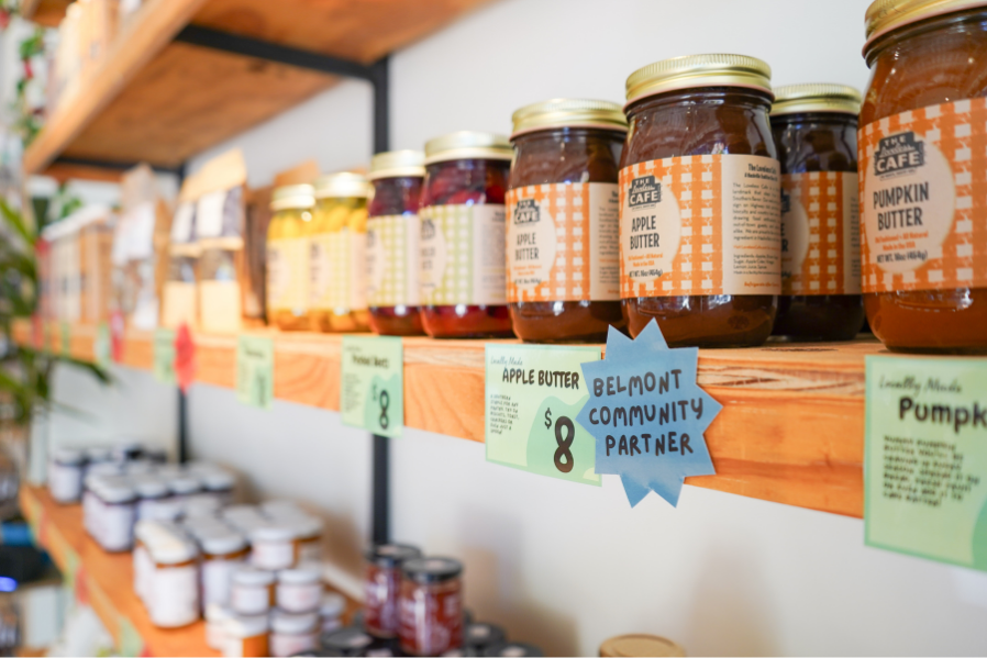 Jars of apple and pumpkin butters on wooden shelves in a store.