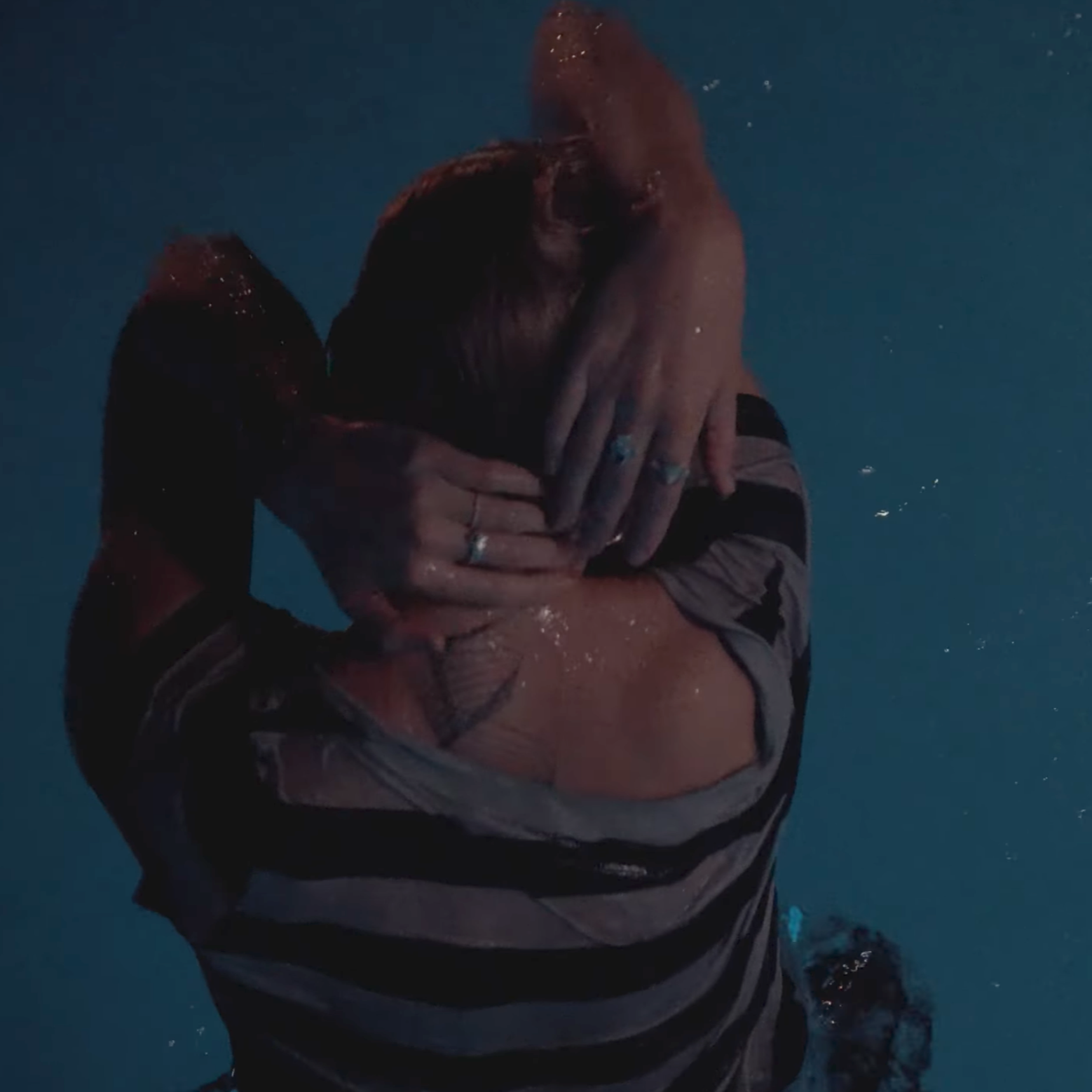 A person holding a puppy in the water, hugging it with both hands.
