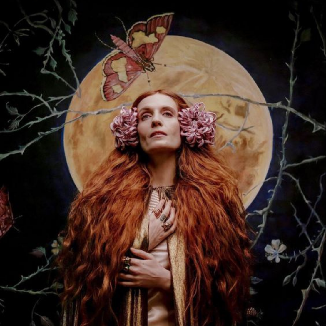 A woman with long, wavy red hair wearing floral headpieces, a fur coat, and jewelry, with a large moon and a butterfly in the background.