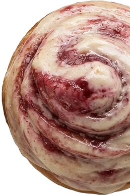 Close-up of a cinnamon roll with white icing and a swirl of red fruit filling