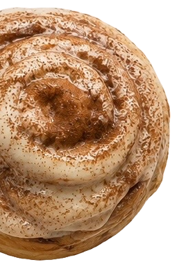 Close-up of a cinnamon roll with icing and cinnamon dusting.