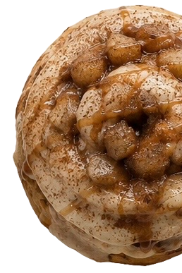 A close-up of a dessert with chopped bananas and caramel sauce on top of a whipped cream topping on a waffle cone.