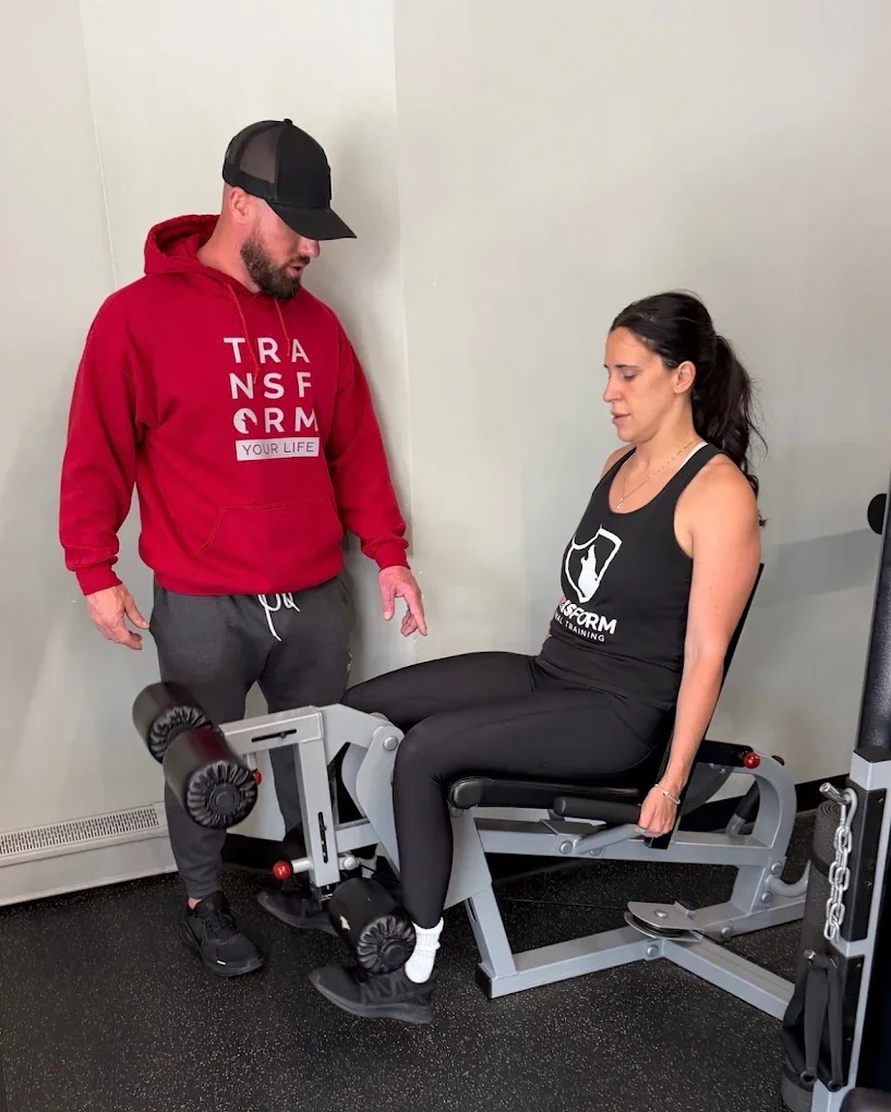 Trainer guiding a client on one-on-one personal training through a leg exercise.