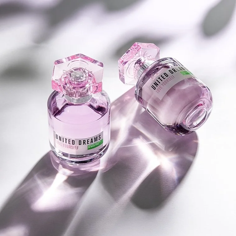 Two bottles of pastel pink nail polish with clear glass caps on a white surface with shadows.