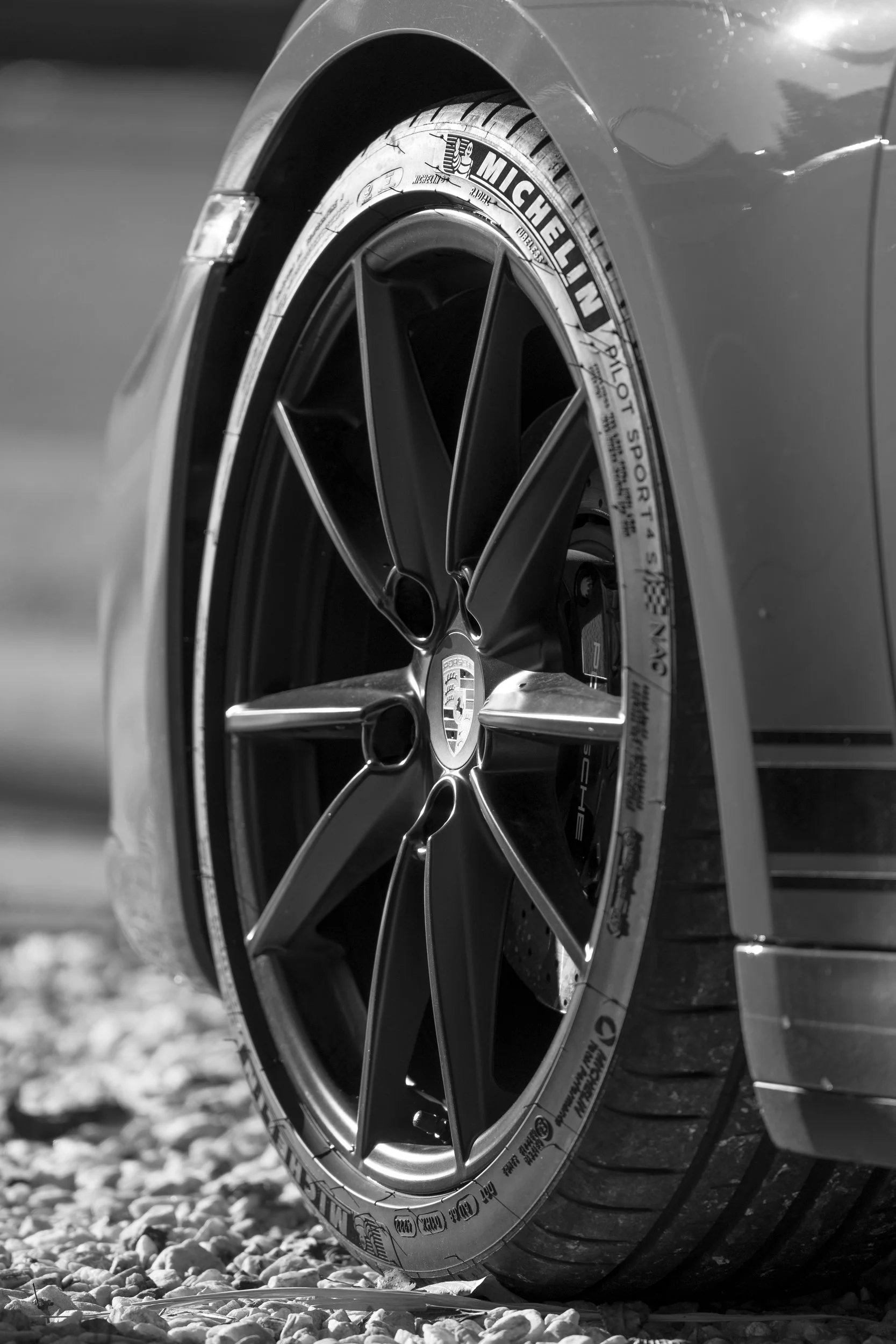 Nahaufnahme einer Felge und eines Michelin-Reifens auf Kies in Schwarzweiß – Detailfotografie von Cine Cat Production