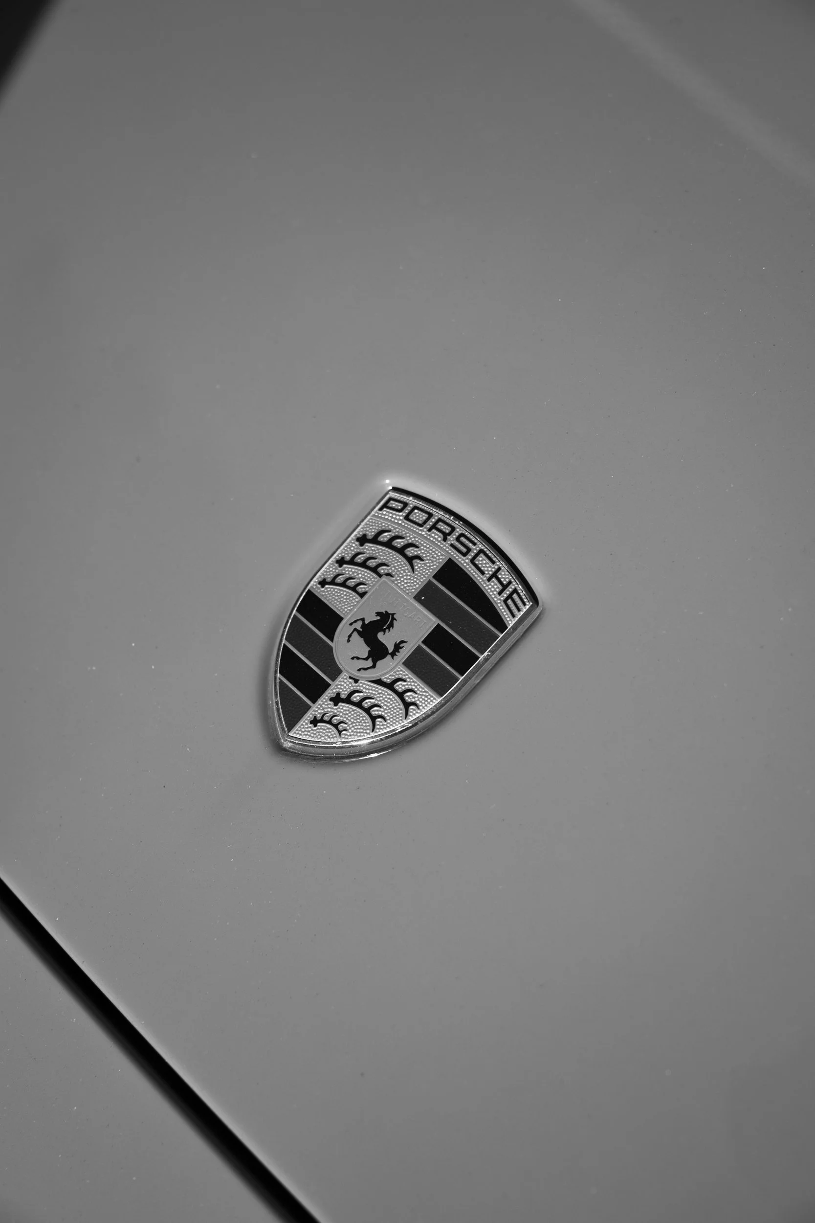 Porsche-Wappen auf der Fronthaube in Schwarzweiß – Detailaufnahme
