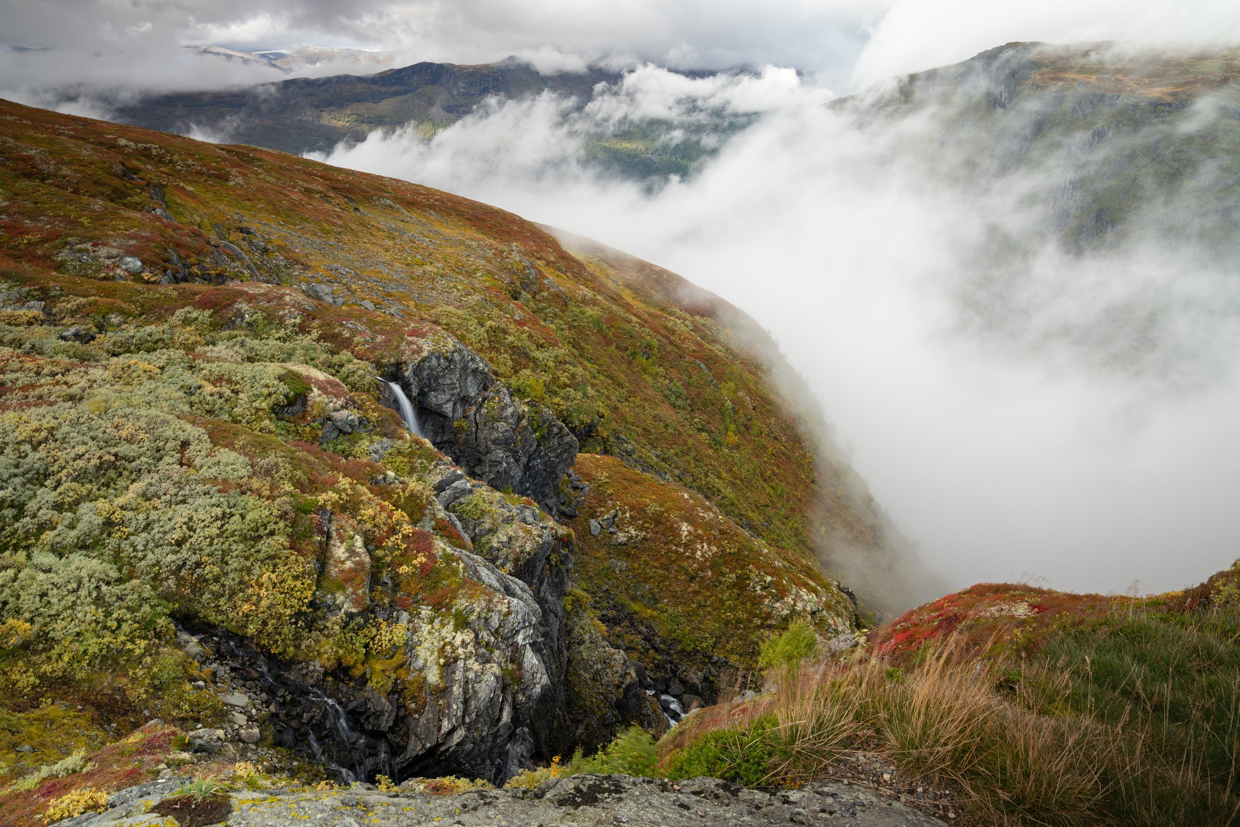 Nebel zieht über eNebel zieht über Berghänge mit Wasserfall in Norwegen – Landschaftsfotografie von Leon Hartmanninen Berghängen mit Wasserfall in Norwegen – Landschaftsfotografie von Leon Hartmann