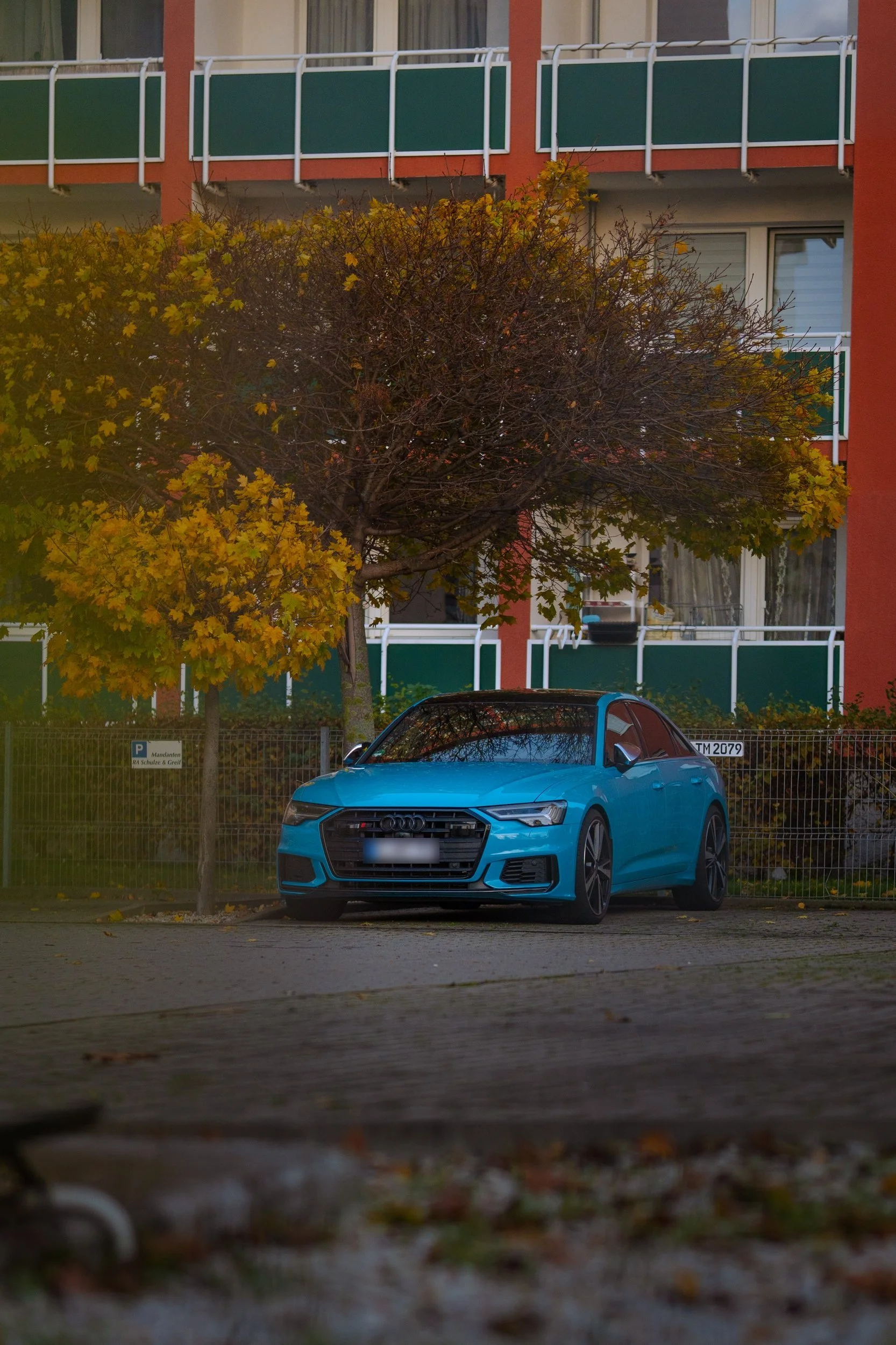 Blauer Audi vor einem Wohnhaus im Herbst – Fahrzeugfotografie
