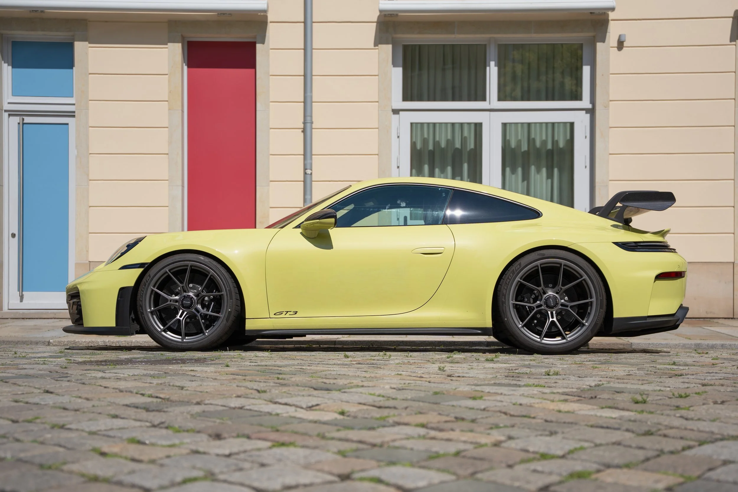 Gelber Porsche 911 GT3 in der Seitenansicht vor einer Altbaufassade – Fahrzeugfotografie von Cine Cat Production