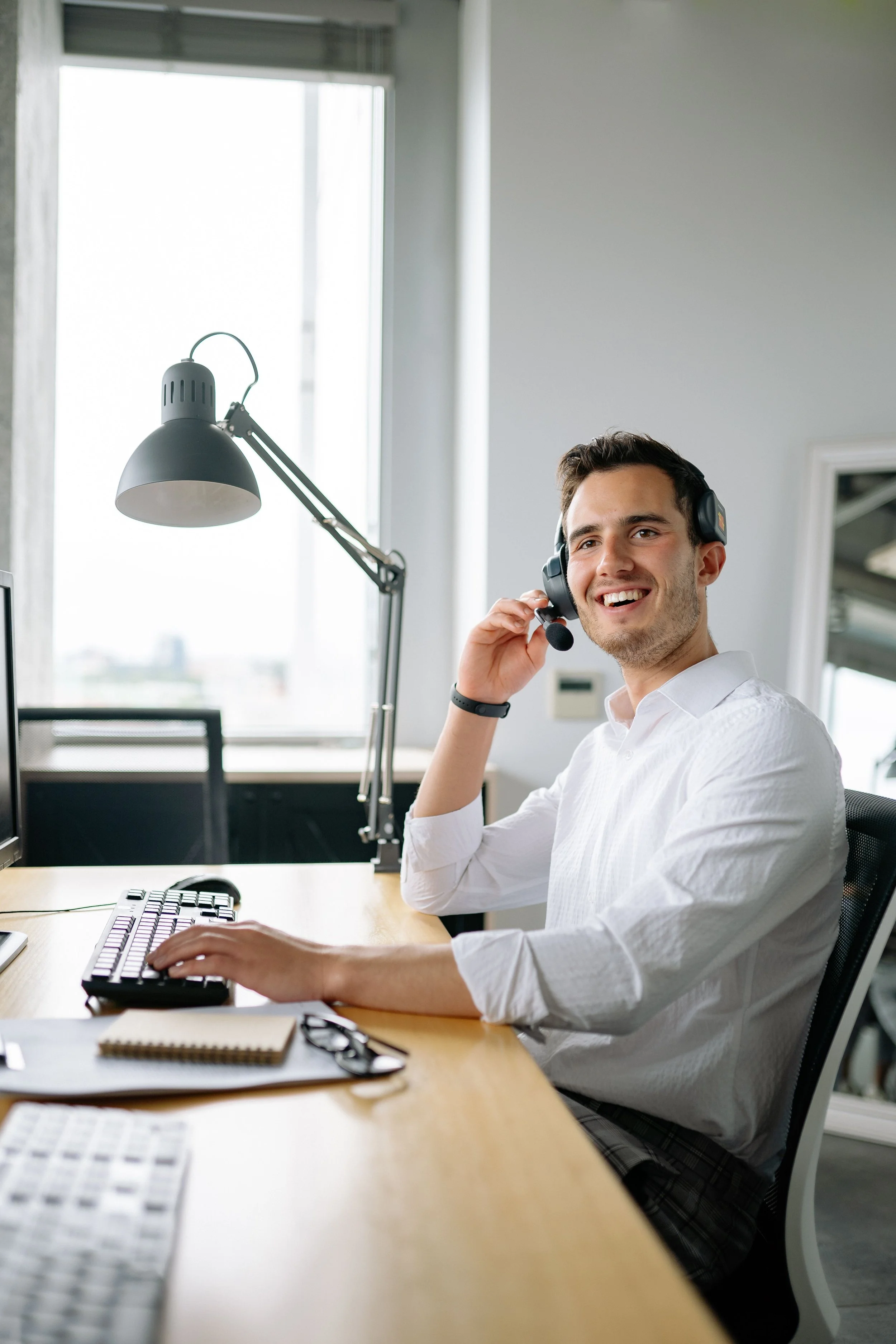A support professional wearing a headset at a laptop.