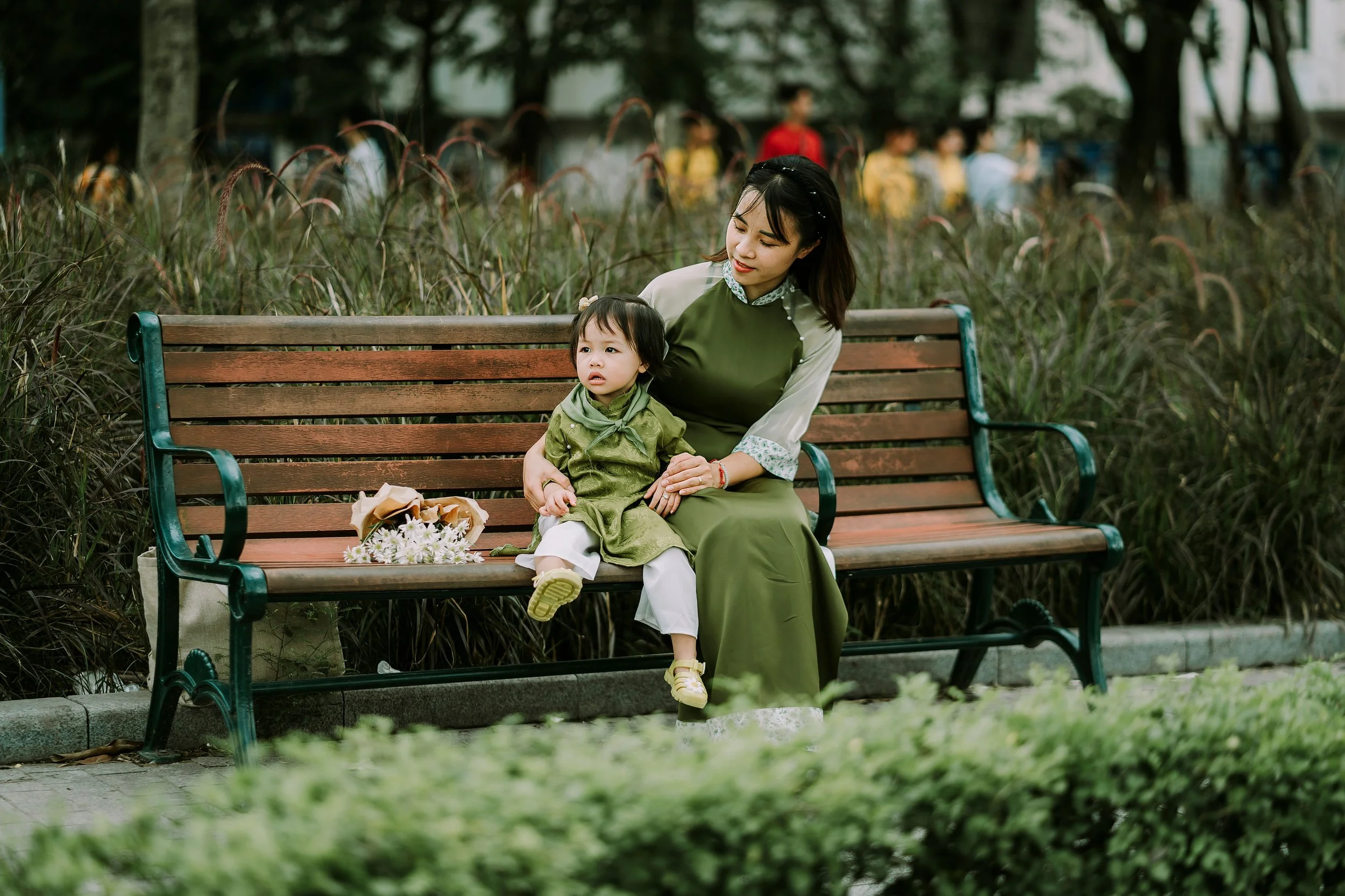 A woman and child sitting together on a park bench.