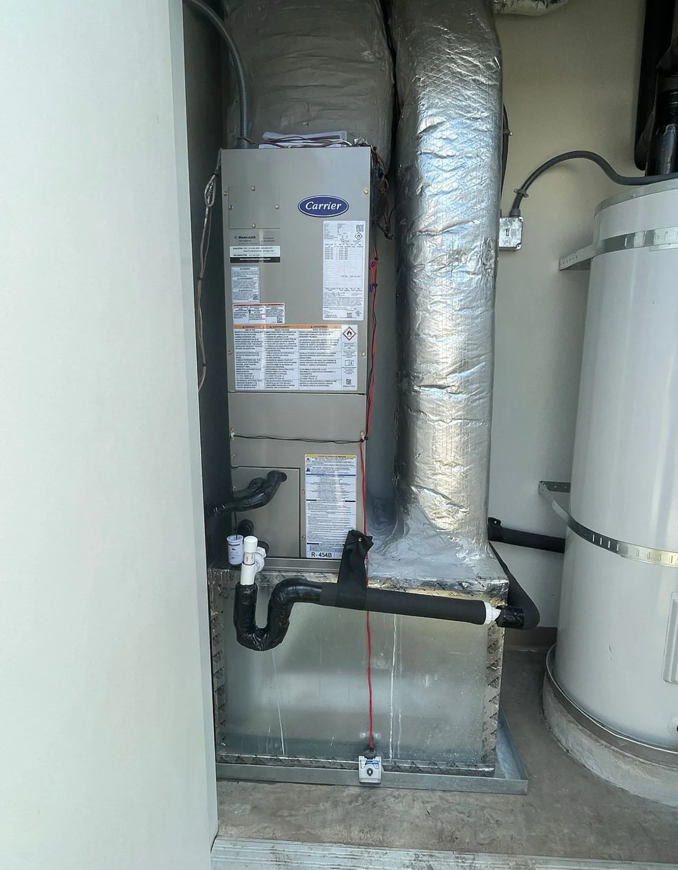 HVAC system with a Carrier furnace, insulated ductwork, and a water heater in a utility closet.