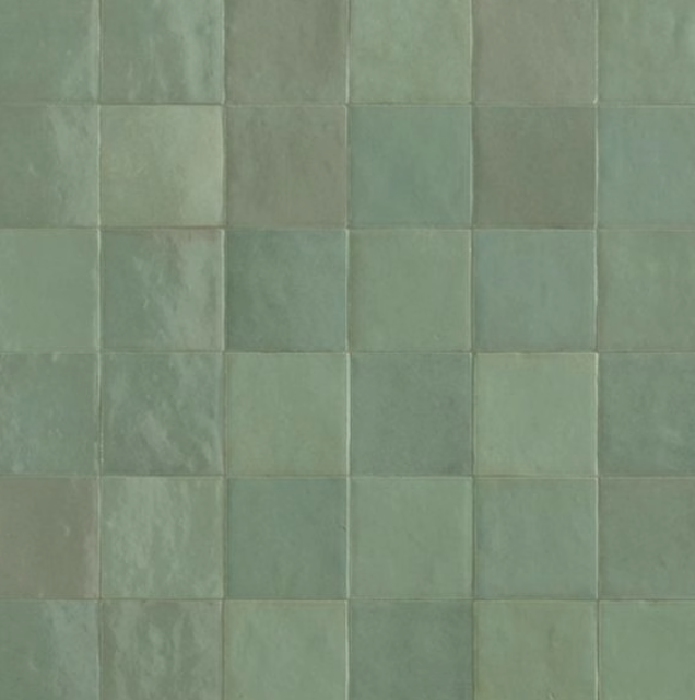 Close-up of a wall made of green ceramic tiles arranged in a grid pattern.