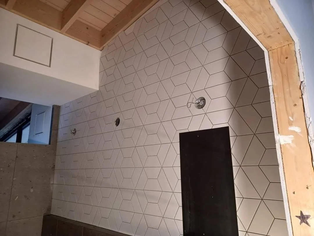 Tile floor with geometric pattern, electrical fixtures, and unfinished wooden wall and framing.