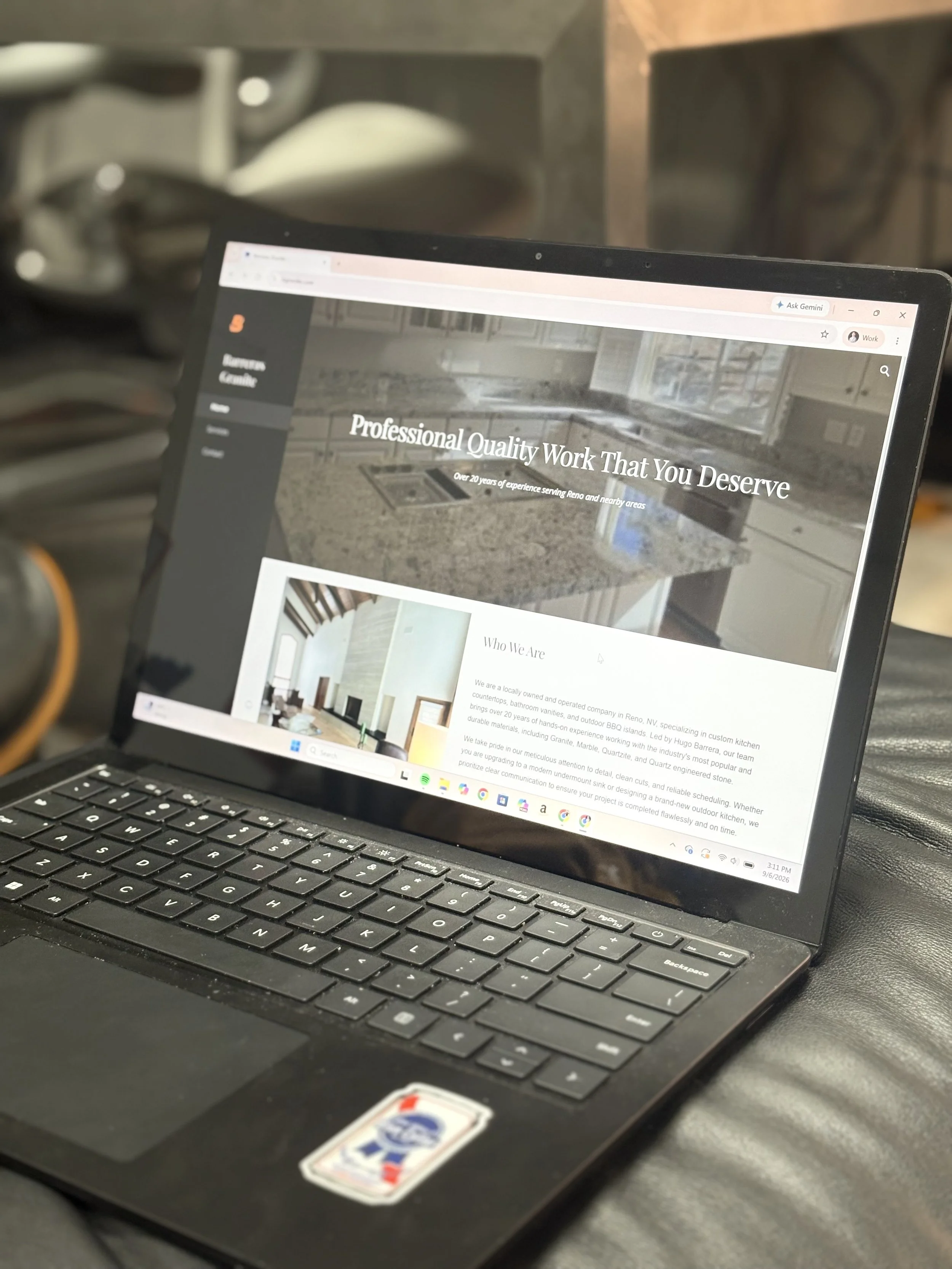 A laptop computer displaying a website about kitchen remodeling, placed on a dark surface with blurred kitchen items in the background.