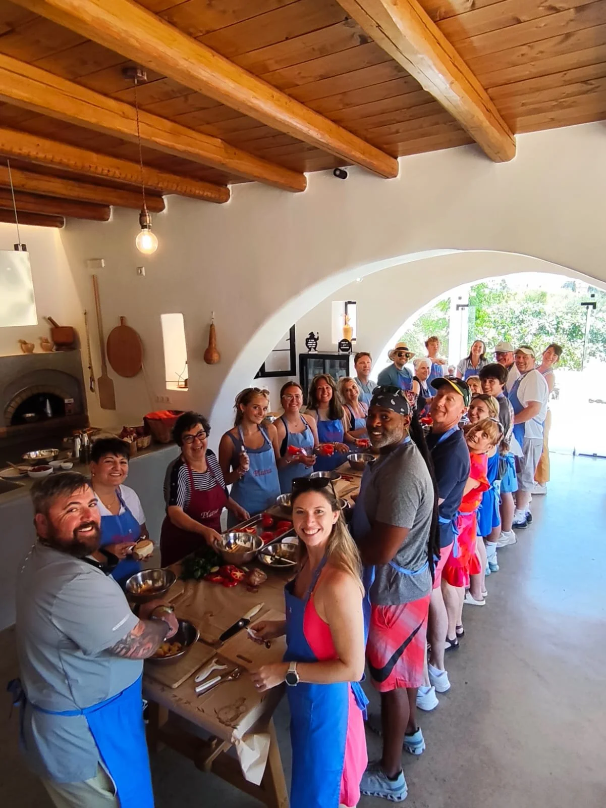 Greece travelers in aprons preparing food together around the family kitchen table.