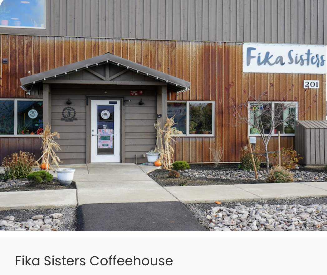 Exterior of Fika Sisters Coffeehouse with fall decorations, pumpkins, and a sign.