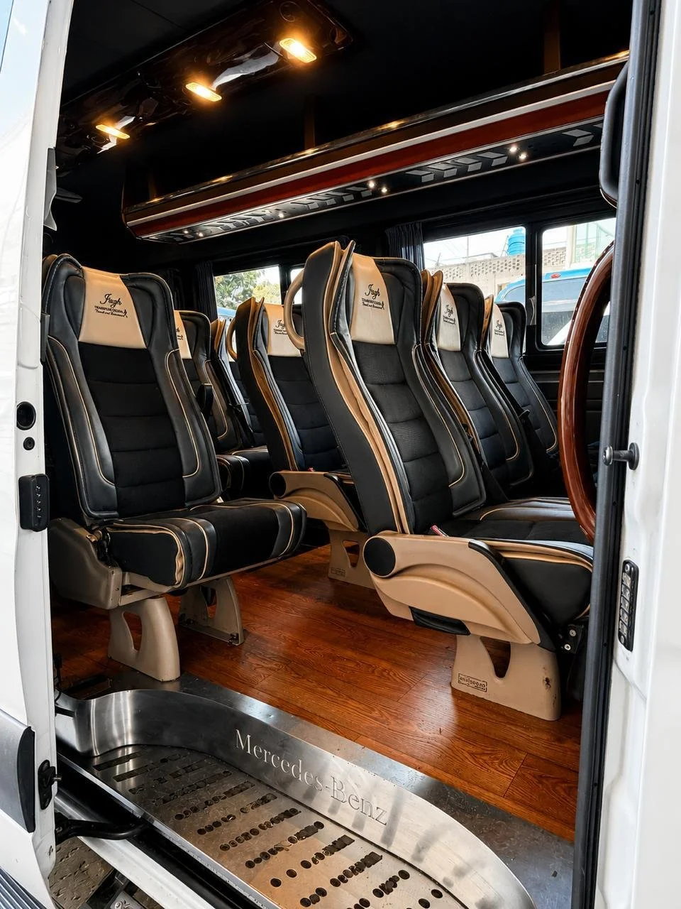 Asientos de autobús de lujo en un autobús Mercedes-Benz, con ventanas grandes y piso de madera.