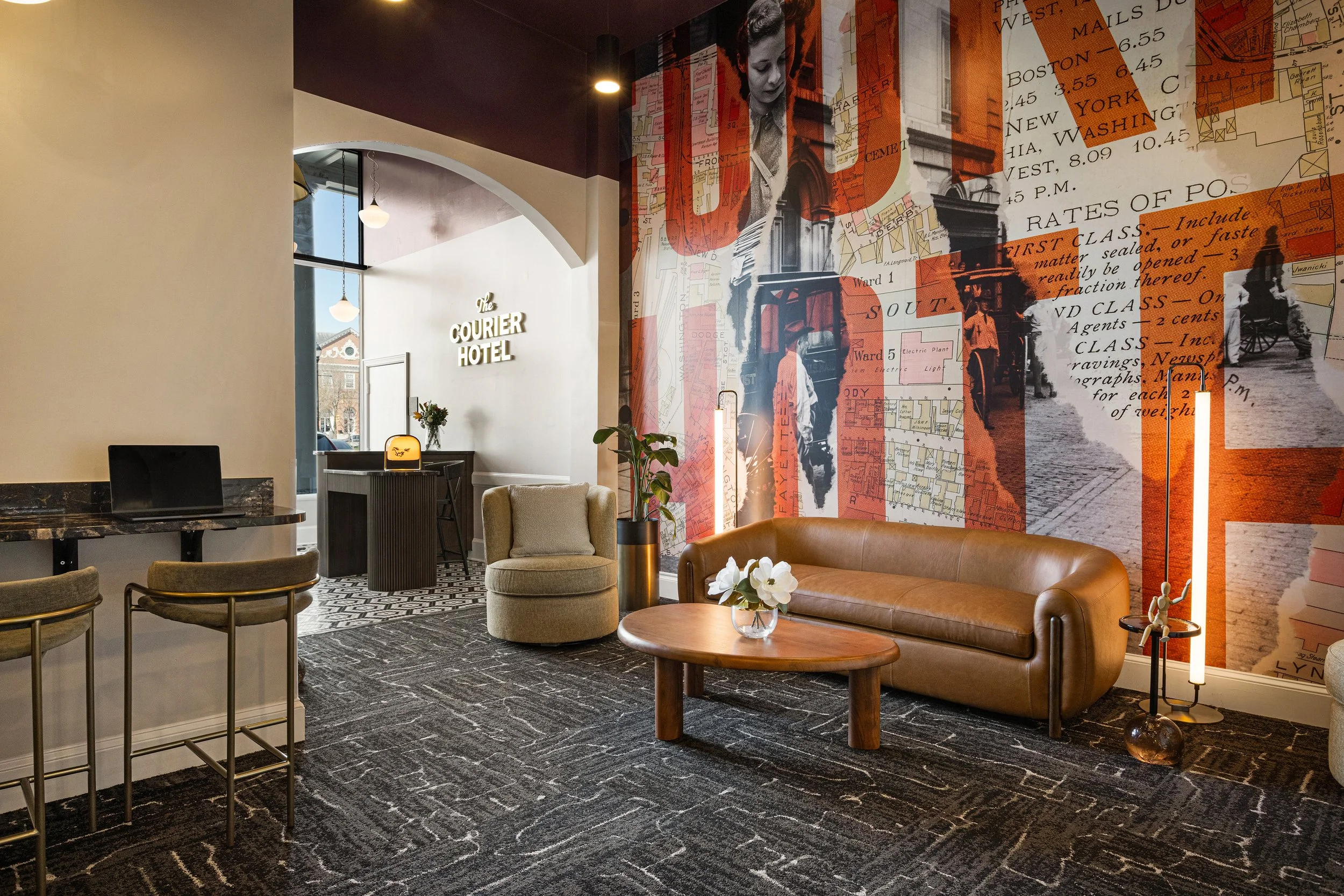 Stylish lobby at The Courier Hotel with leather sofa, lounge chairs, coffee table, and historic map mural