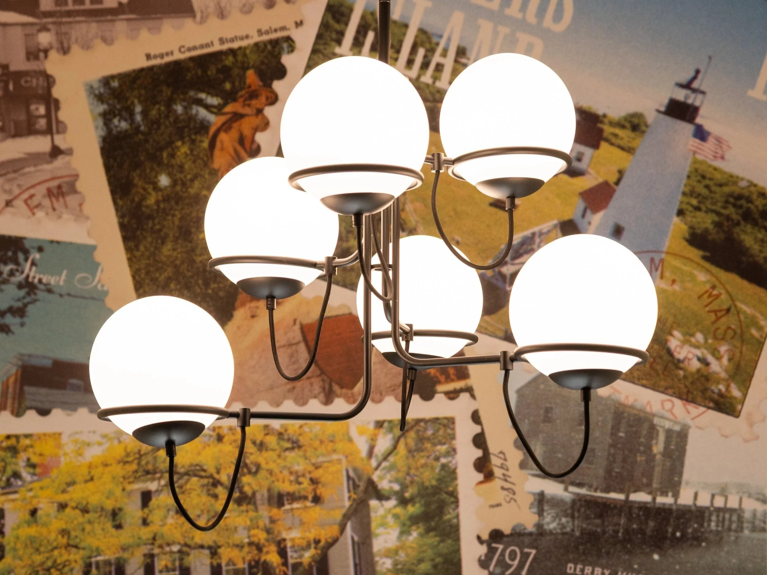 Multi-light chandelier with glowing white globe shades against a vintage newspaper collage background