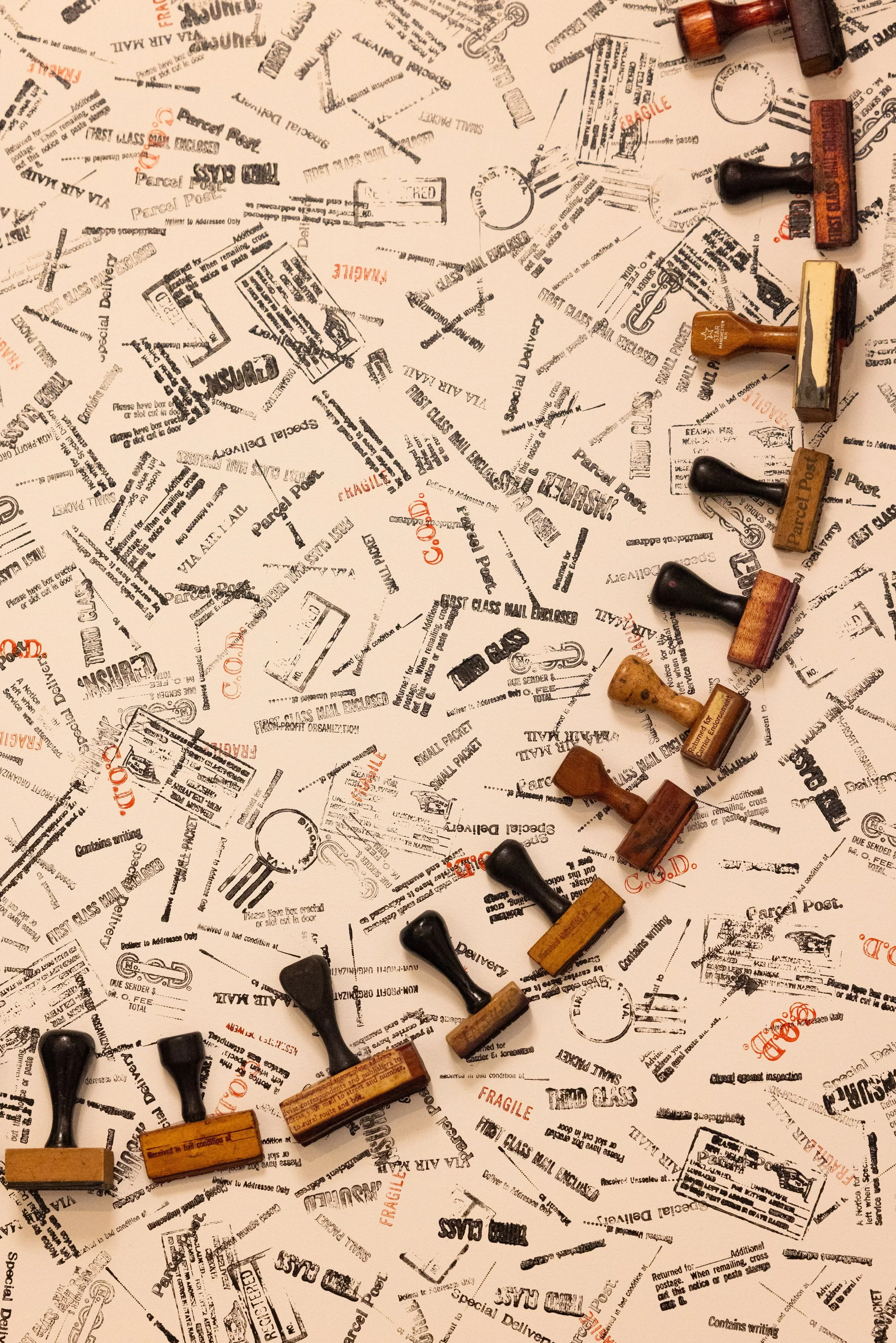 Vintage rubber postal stamps scattered across a surface covered with retro mail and parcel imprint designs