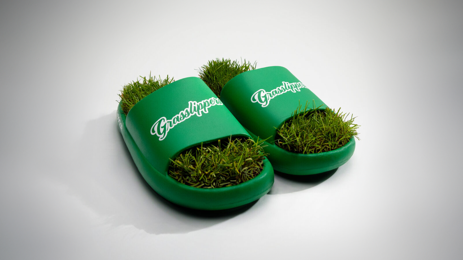 Green grass-filled slides with “Grassslippers” branding