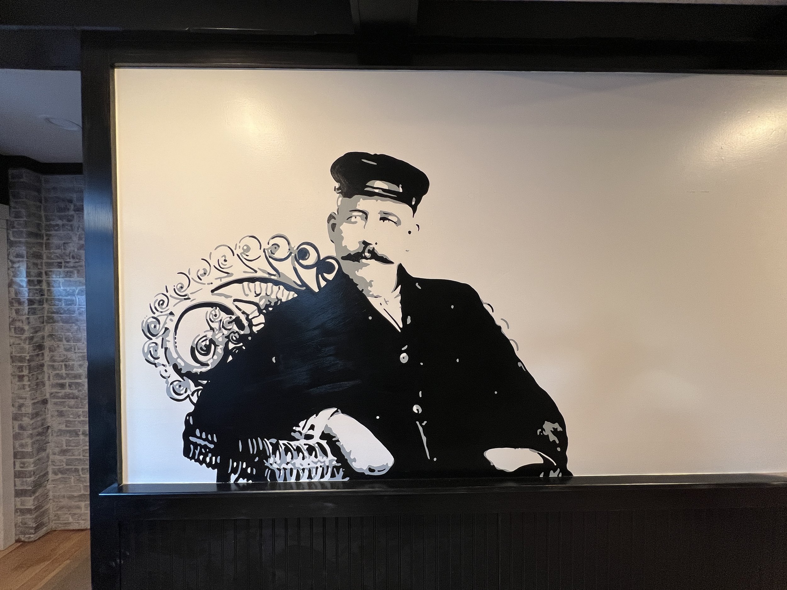 Black-and-white artwork of a uniformed man reclining beside an ornate armchair in a framed display above a fireplace