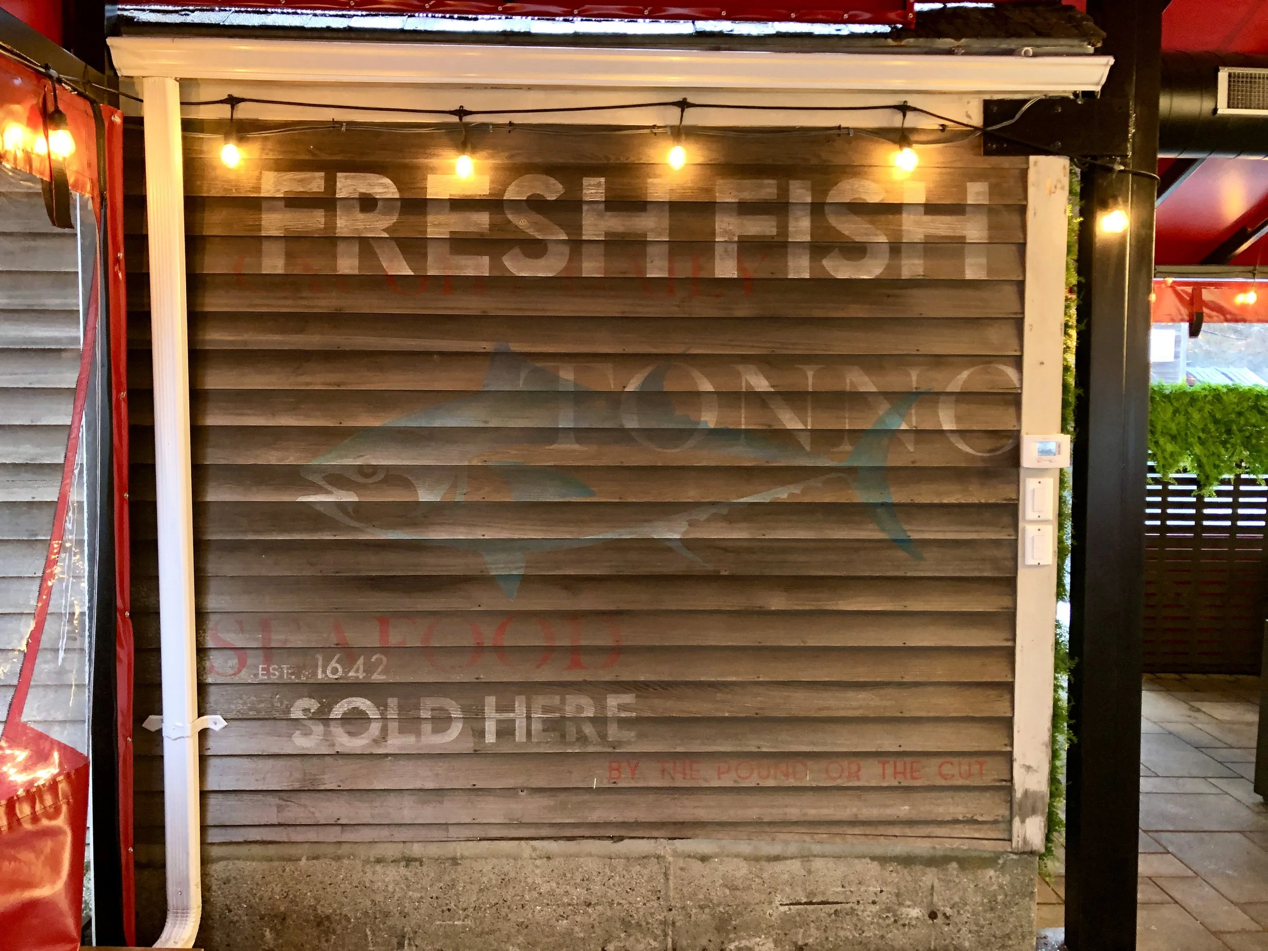 Rustic wooden restaurant facade with string lights and faded painted lettering reading “Ribs, Ribs, Ribs” and “Barbecue.”