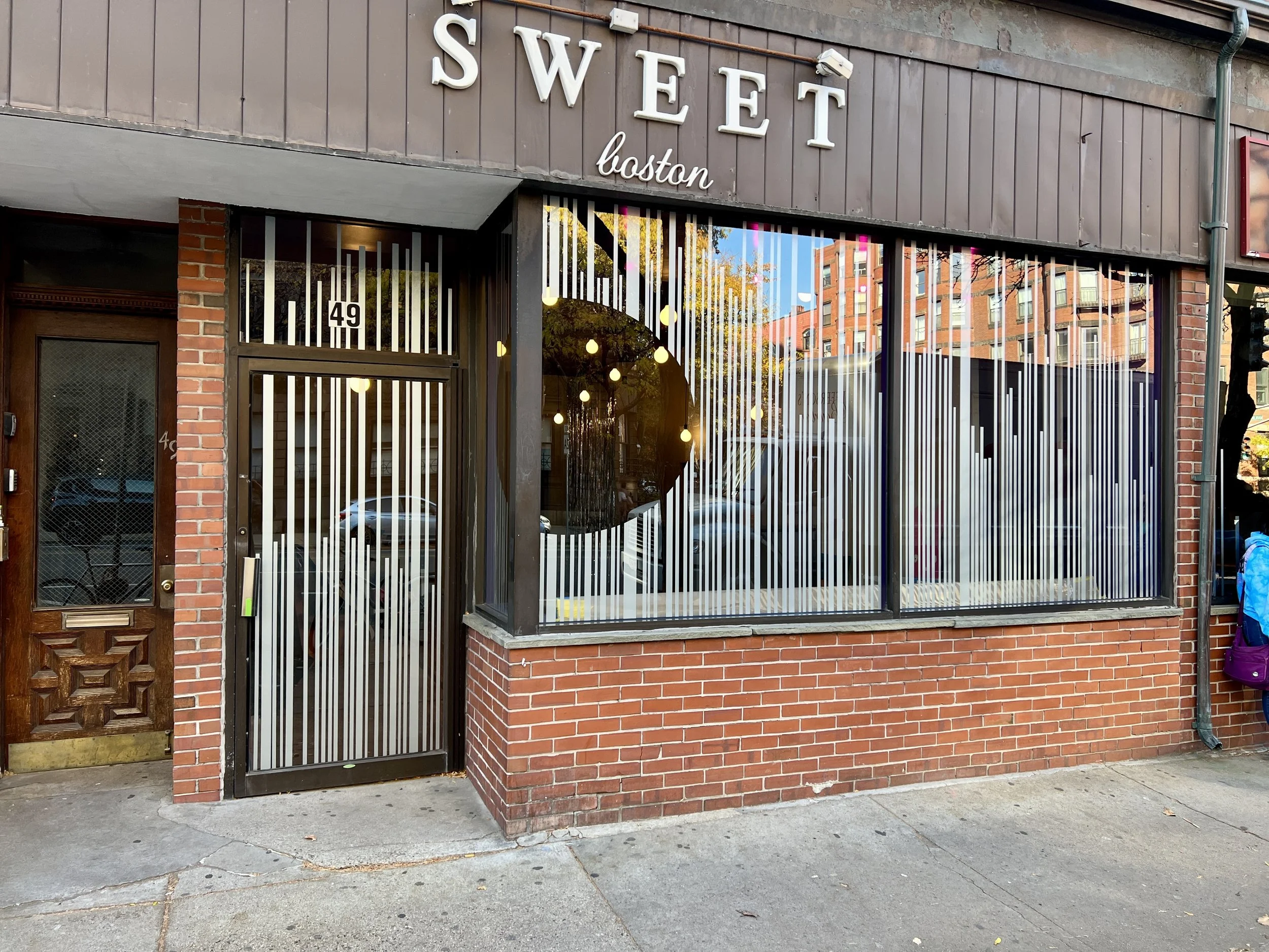 Exterior storefront of Sweet Boston with striped windows and brick facade
