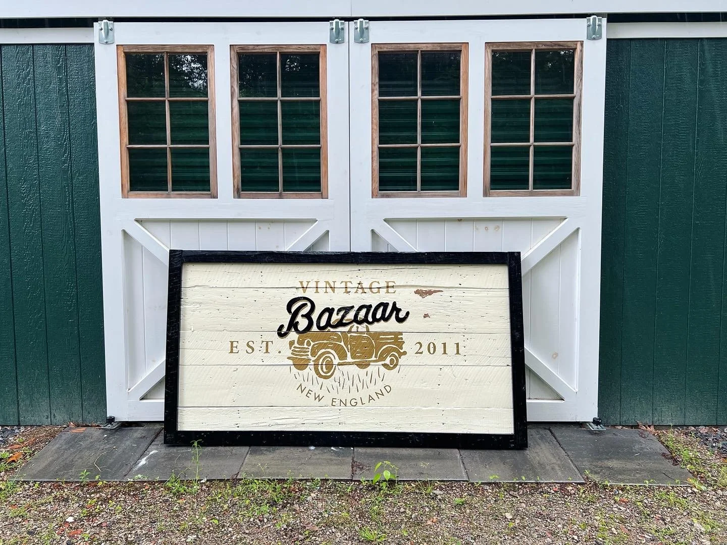 Vintage Bazaar New England sign leaning against white barn doors