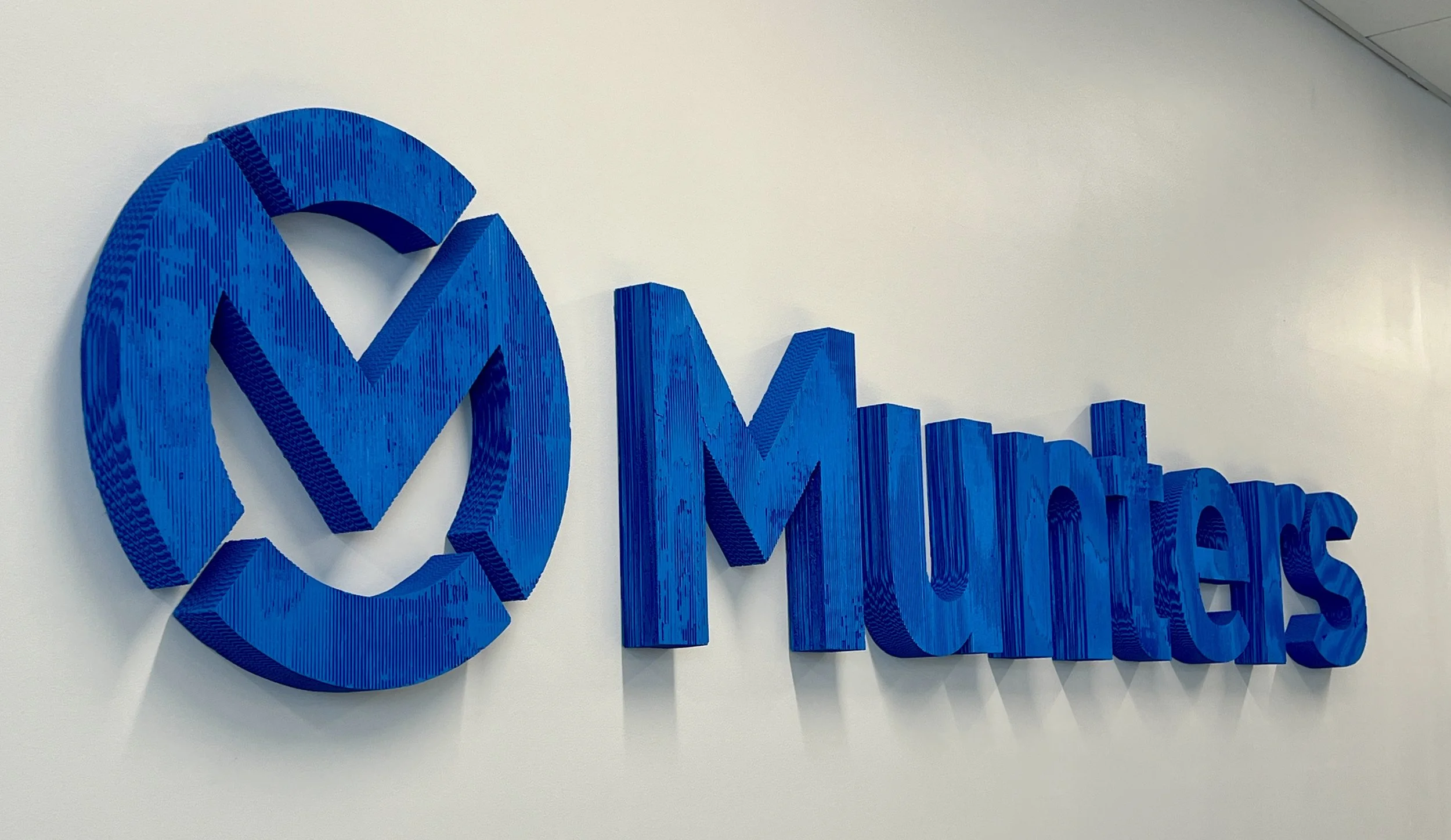 Blue three-dimensional “M Matters” logo mounted on a white wall
