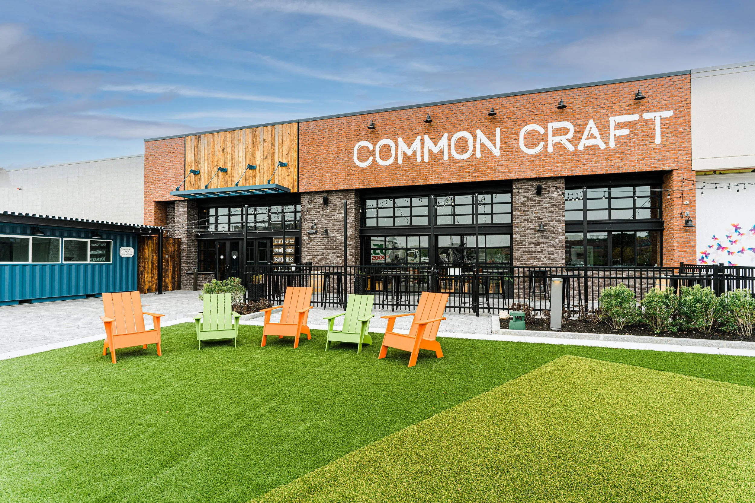 Exterior of Common Craft brewery and restaurant with brick facade, outdoor patio, and colorful Adirondack chairs